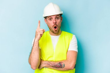 Kafkasyalı genç işçi, mavi arka planda izole edilmiş. Harika bir fikri var. Yaratıcılık kavramı..