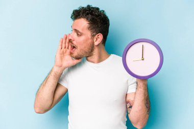 Elinde bir saat tutan beyaz bir adam mavi arka planda izole edilmiş bağırıyor ve avuç içini açık tutuyordu..