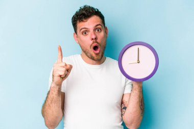 Elinde mavi arka planda bir saat tutan beyaz bir adam. Harika bir fikri var, yaratıcılık kavramı..