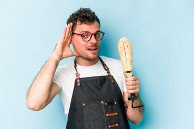 Kafkasyalı genç kunduracı, mavi arka planda izole edilmiş bir şekilde bir dedikoduyu dinlemeye çalışıyor..