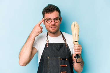 Kafkasyalı genç kunduracı, mavi arka planda izole edilmiş, işaret parmağıyla yaptığı hayal kırıklığı jestini gösteriyor..