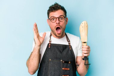 Kafkasyalı genç kunduracı mavi arka planda izole edilmiş, şaşırmış ve şok olmuş..