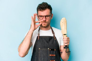 Kafkasyalı genç kunduracı mavi arka planda izole edilmiş ve parmakları dudaklarında bir sır saklıyor..