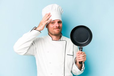 Kafkasyalı genç aşçı elinde uçan bir tavayla mavi arka planda mahsur kaldı..