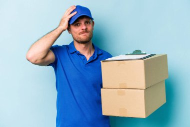 Kafkasyalı genç teslimatçı mavi arka planda izole edilmiş şokta, önemli bir toplantıyı hatırladı..