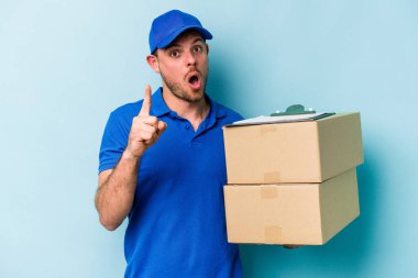 Kafkasyalı genç teslimatçı mavi arka planda izole edilmiş. Bir fikri var, ilham verici bir kavram..