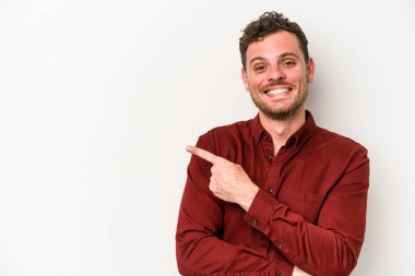 Beyaz arka planda izole edilmiş genç beyaz adam işaret parmağıyla işaret ederek gülümsüyor..