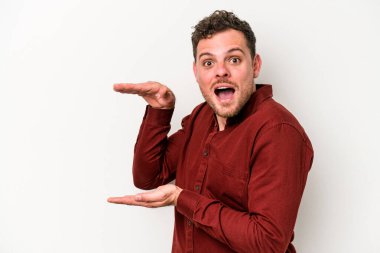 Beyaz arka planda izole edilmiş genç beyaz adam elleri arasında bir kopya alanı tutarken şok ve hayrete düştü..