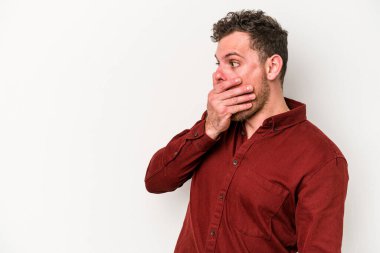 Beyaz arka planda izole edilmiş beyaz tenli genç adam ağzını eliyle kapatan bir fotokopi odasına bakıyor..