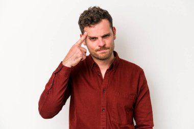 Beyaz arka planda izole edilmiş genç beyaz bir adam şakağı parmağıyla işaret ediyor, düşünüyor ve bir göreve odaklanıyor..