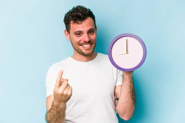 Young Caucasian Man Holding Clock Isolated Blue Background Pointing Finger — Stock Fotó
