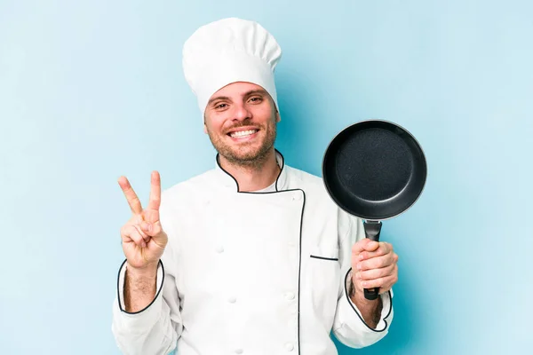 Young Caucasian Chef Man Holding Flying Pan Isolated Blue Background — Zdjęcie stockowe