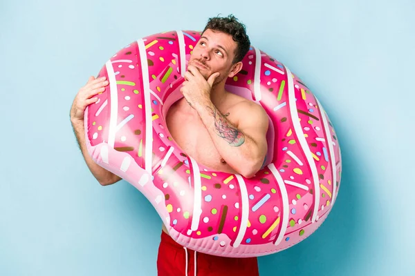 Young Caucasian Man Holding Inflatable Donut Isolated Blue Background Looking —  Fotos de Stock