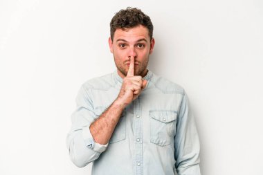 Beyaz arka planda izole edilmiş genç beyaz bir adam ya sır saklıyor ya da sessizlik istiyor..