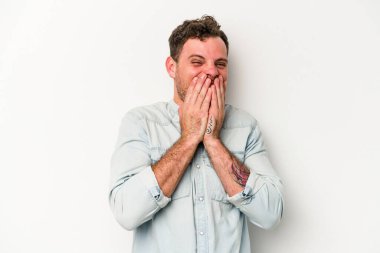 Beyaz arka planda izole olmuş genç beyaz bir adam bir şeye gülüyor, ağızlarını ellerle kapatıyor..