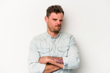 Beyaz arka planda izole edilmiş genç beyaz adam alaycı bir ifadeyle kameraya bakıyor..