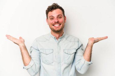 Beyaz arka planda izole genç beyaz adam kollarıyla ölçek yapar, mutlu ve kendinden emin hisseder..