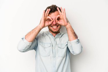 Beyaz arka planda izole edilmiş genç beyaz bir adam gözlerinde sorun olmadığını gösteriyor.