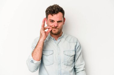 Beyaz arka planda izole edilmiş beyaz tenli genç bir adam parmakları dudaklarında bir sır saklıyor..