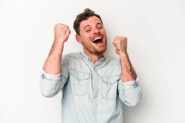 Beyaz arka planda izole edilmiş genç beyaz bir adam zaferi, tutkuyu ve coşkuyu kutluyor, mutlu bir ifade..