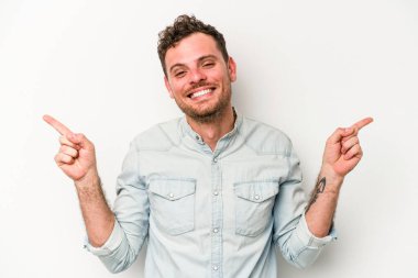 Beyaz arka planda izole edilmiş genç beyaz bir adam farklı kopya alanlarını gösteriyor, birini seçiyor, parmaklarıyla gösteriyor..