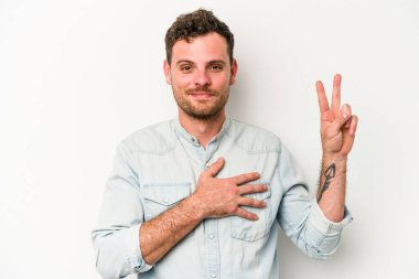 Beyaz arka planda izole edilmiş genç beyaz adam yemin ediyor, elini göğsüne koyuyor..