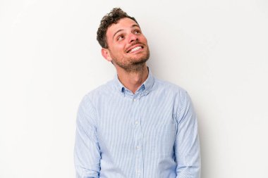 Beyaz arka planda izole edilmiş genç beyaz adam gevşemiş ve mutlu bir şekilde gülüyor, boynunda dişlerini gösteriyor..
