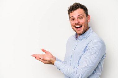 Beyaz arka planda izole edilmiş beyaz tenli genç bir adam palmiyesinde bir kopya alanı tutuyor..