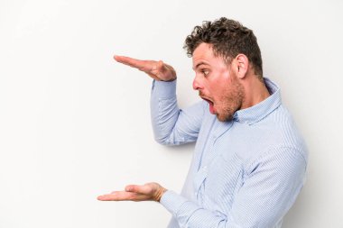 Beyaz arka planda izole edilmiş genç beyaz adam elleri arasında bir kopya alanı tutarken şok ve hayrete düştü..