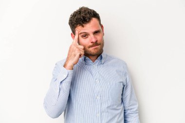 Beyaz arka planda izole edilmiş genç beyaz bir adam şakağı parmağıyla işaret ediyor, düşünüyor ve bir göreve odaklanıyor..