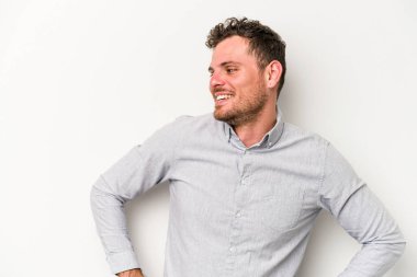 Beyaz arka planda izole genç beyaz adam mutlu bir şekilde gülüyor ve ellerini karnının üstünde tutarak eğleniyor..