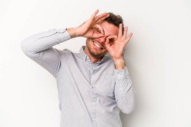 Beyaz arka planda izole edilmiş genç beyaz bir adam gözlerinde sorun olmadığını gösteriyor.