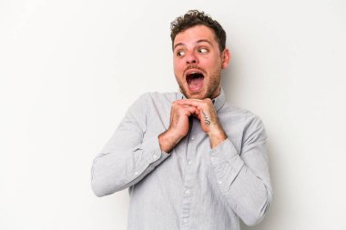 Beyaz arka planda izole genç beyaz adam ellerini çenesinin altında tutuyor, mutlu bir şekilde yana bakıyor..