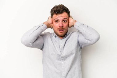 Beyaz arka planda izole edilmiş genç beyaz bir adam kulakları kulaklarıyla kapatıyor ve çok ses duymamaya çalışıyor..