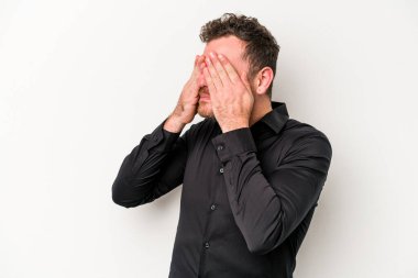 Beyaz arka planda izole edilmiş genç beyaz bir adam elleriyle gözlerini kapatmaktan korkuyor..
