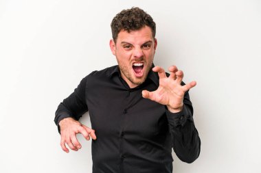 Beyaz arka planda izole edilmiş genç beyaz bir adam pençelerini kedi taklidi yaparken gösteriyor, agresif bir hareket..