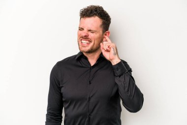 Beyaz arka planda izole edilmiş genç beyaz bir adam parmaklarıyla kulaklarını kapatıyor, gürültülü bir ortam yüzünden stresli ve çaresiz..