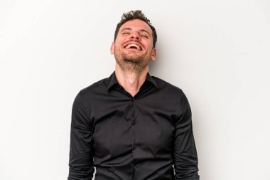 Beyaz arka planda izole edilmiş genç beyaz adam gevşemiş ve mutlu bir şekilde gülüyor, boynunda dişlerini gösteriyor..