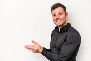 Beyaz arka planda izole edilmiş beyaz tenli genç bir adam palmiyesinde bir kopya alanı tutuyor..