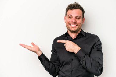 Beyaz arka planda izole edilmiş genç beyaz bir adam, palmiye üzerinde bir fotokopi alanı tutarken heyecanlı..