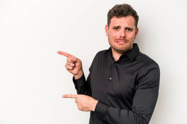 Beyaz arka planda izole edilmiş genç beyaz bir adam işaret parmağıyla fotokopi alanını işaret ederek şok oldu..