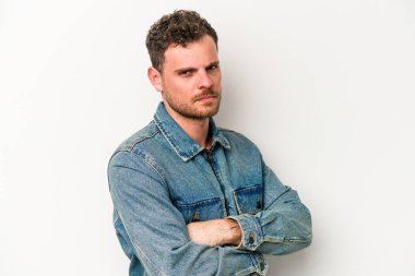 Beyaz arka planda izole edilmiş, hoşnutsuzca kaşlarını çatmış, kollarını kavuşturmuş genç beyaz bir adam..