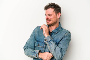 Beyaz arka planda soyutlanmış genç beyaz bir adam kafası karışmış, şüpheli ve güvensiz hissediyor..