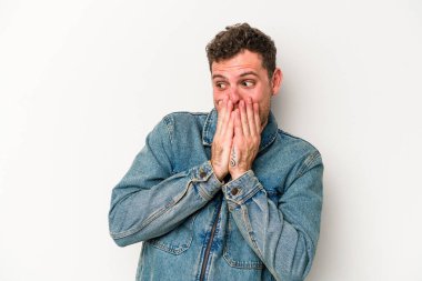 Beyaz arka planda izole olmuş genç beyaz bir adam bir şeye gülüyor, ağızlarını ellerle kapatıyor..
