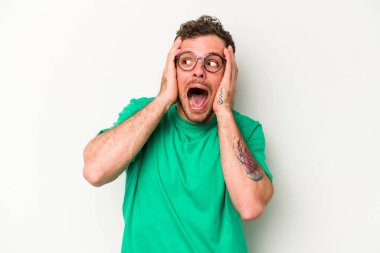 Beyaz arka planda izole edilmiş genç beyaz bir adam kulakları kulaklarıyla kapatıyor ve çok ses duymamaya çalışıyor..