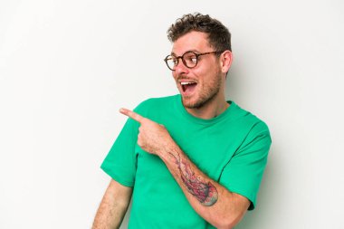 Beyaz arka planda izole edilmiş genç beyaz adam gülümseyen, neşeli ve keyifli bir tarafa bakıyor..