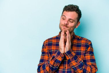 Kafkasyalı genç bir adam mavi arka planda izole edildi. Aklında bir plan kuruyor, bir fikir kuruyor..