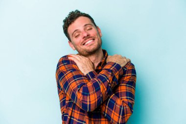 Kafkasyalı genç adam mavi arka planda izole edilmiş, güler yüzlü ve mutlu..