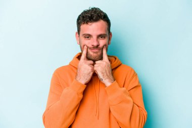 Kafkasyalı genç adam mavi arka planda izole edilmiş iki seçenek arasında şüphe duyuyor.