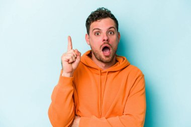 Kafkasyalı genç adam mavi arka planda izole edildi. Harika bir fikri var, yaratıcılık kavramı..